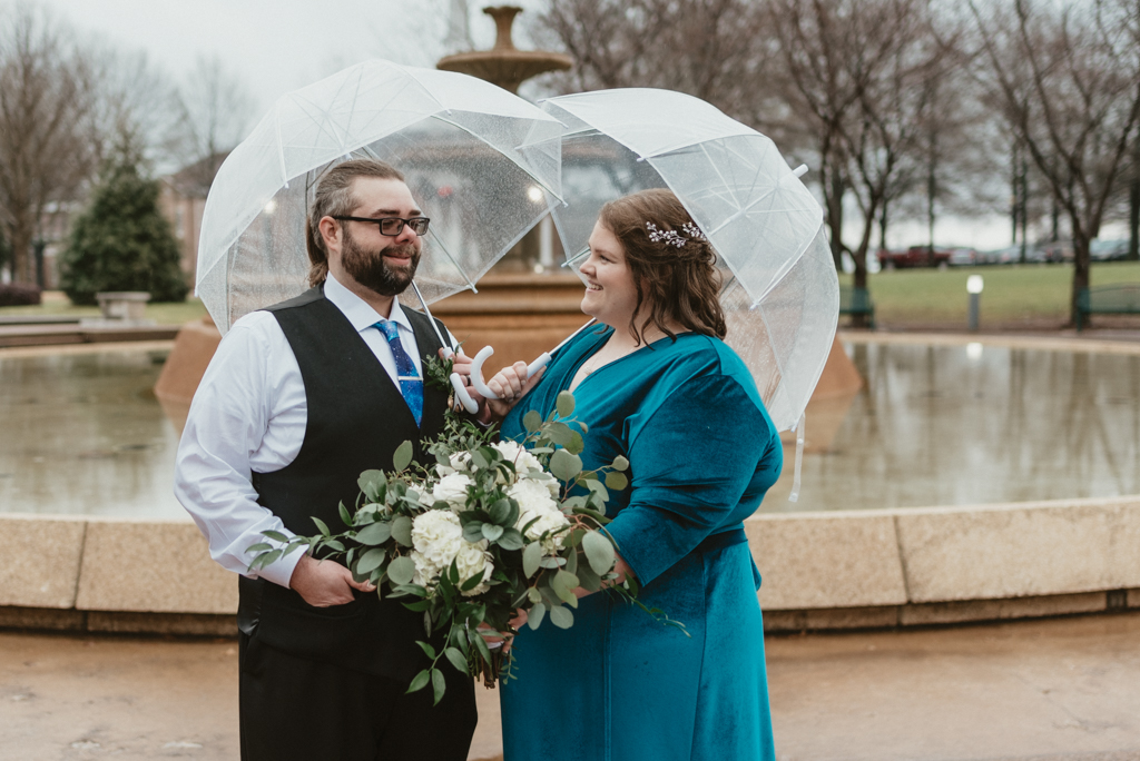 Bride and groom holding umbrellas