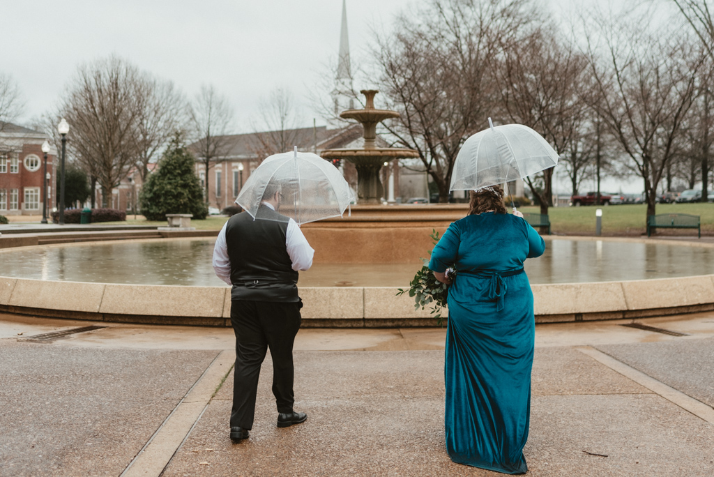 Bride and groom walking with umbrellas