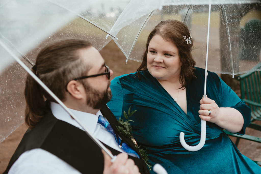 Couple smiling with umbrellas at park