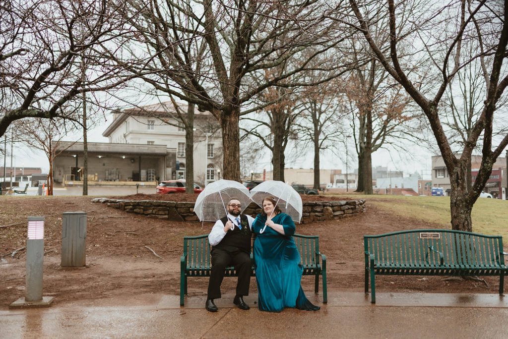 Couple smiling with umbrellas at park