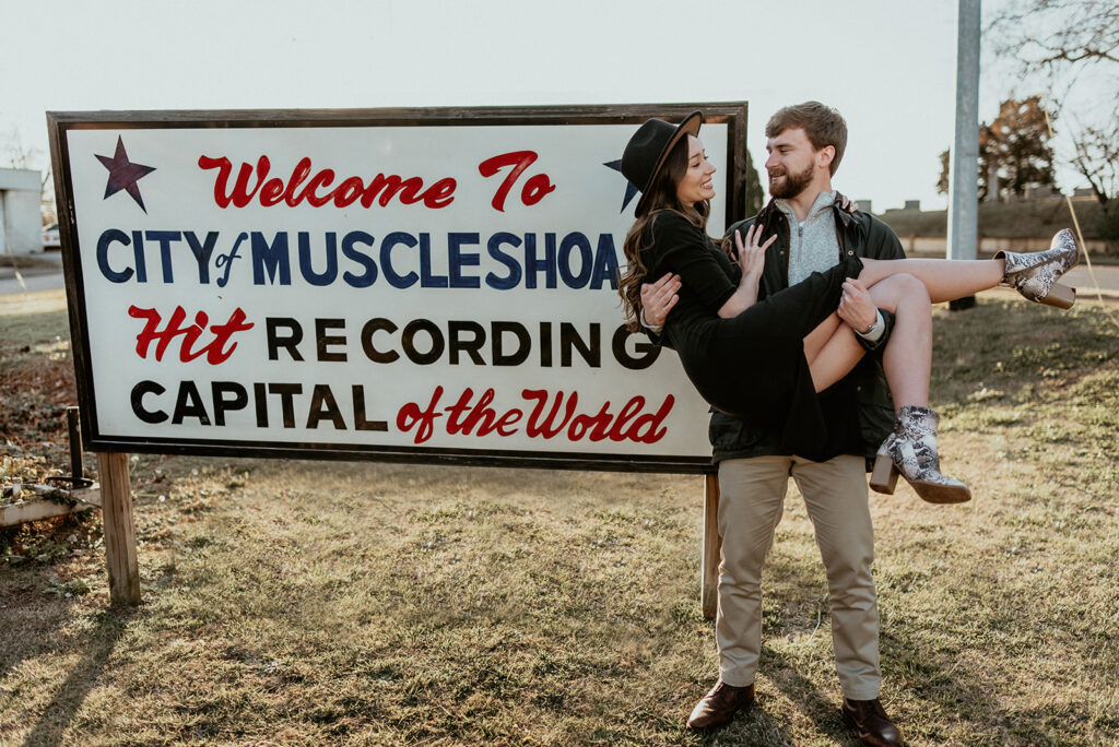 Man holding woman outside of Muscle Shoals Sound Studio sign