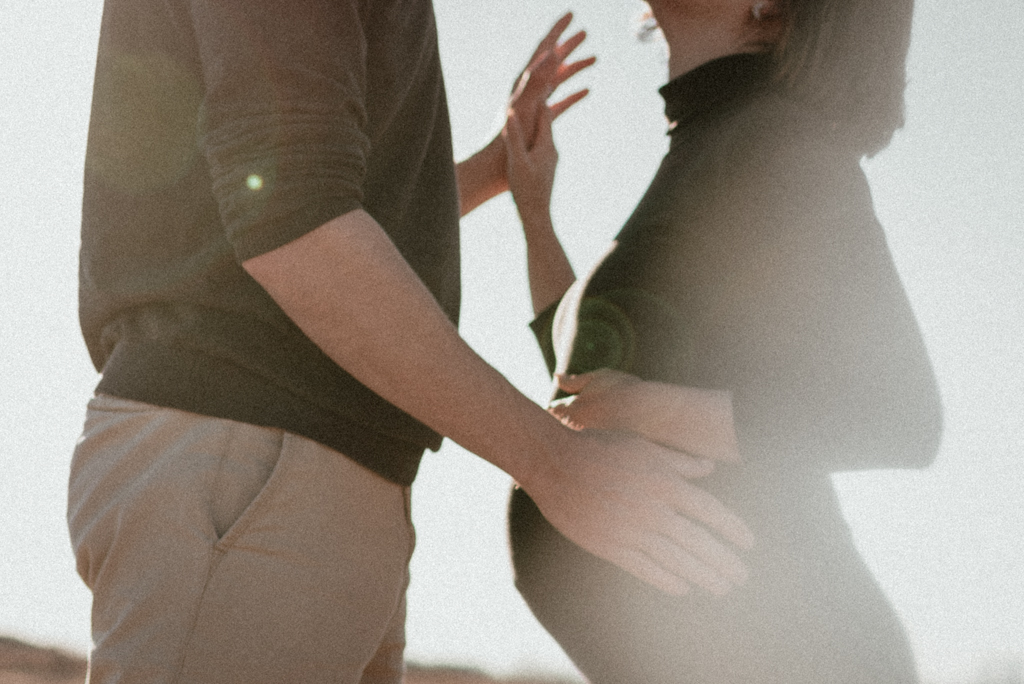Hazy image of man and woman holding hands with pregnant belly