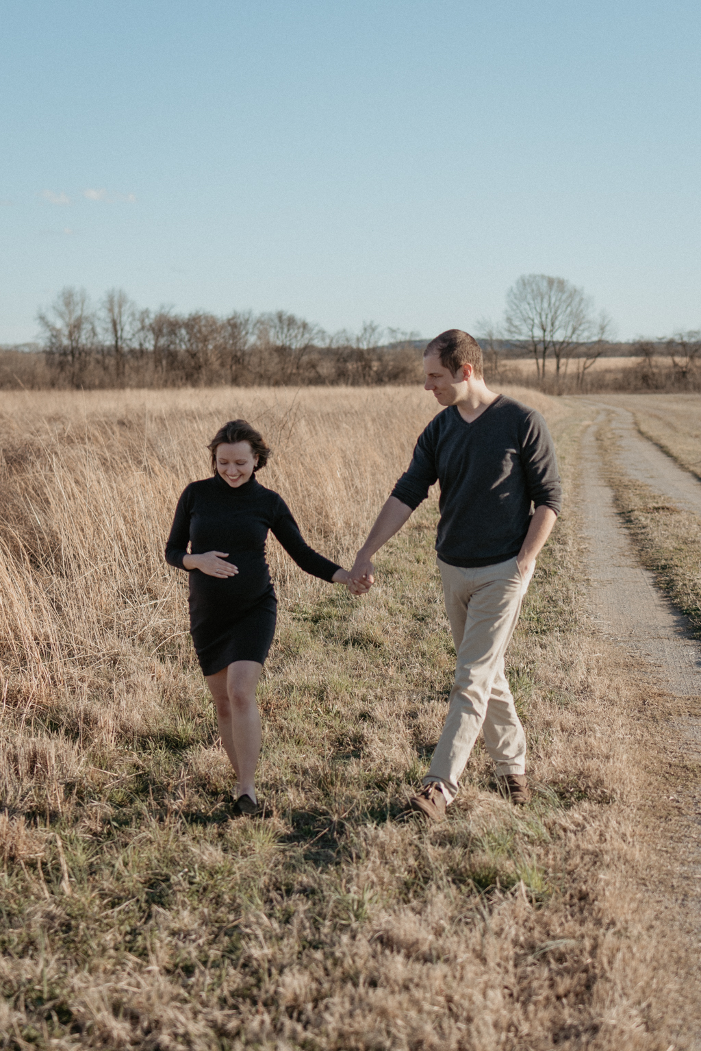 Pregnant couple walking and holding hands while smiling