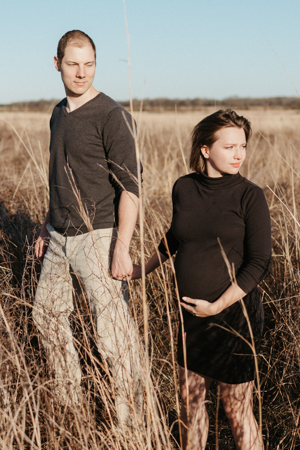 Couple holding hands in tall grass field
