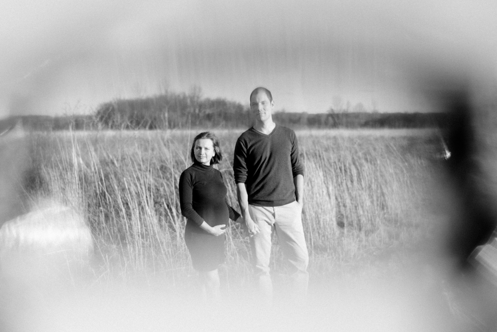 Black and white image of pregnant couple looking at camera