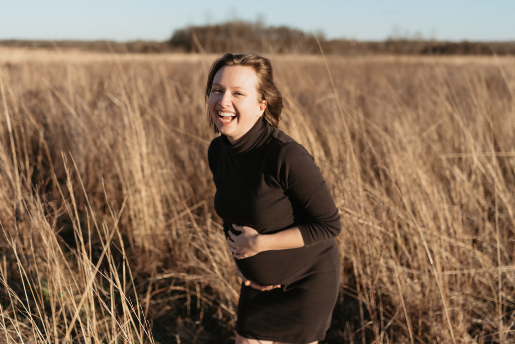 Pregnant woman holding belly and laughing