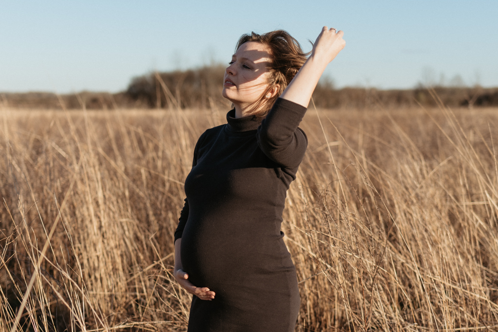 Pregnant woman pushing back hair in the wind