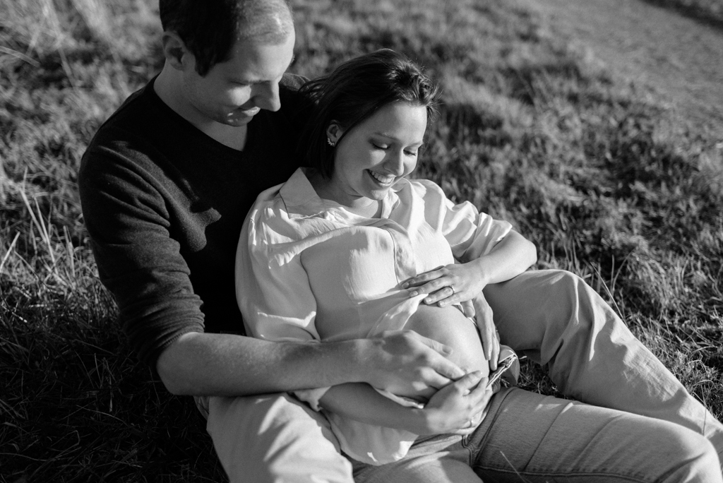 Pregnant couple holding belly and smiling