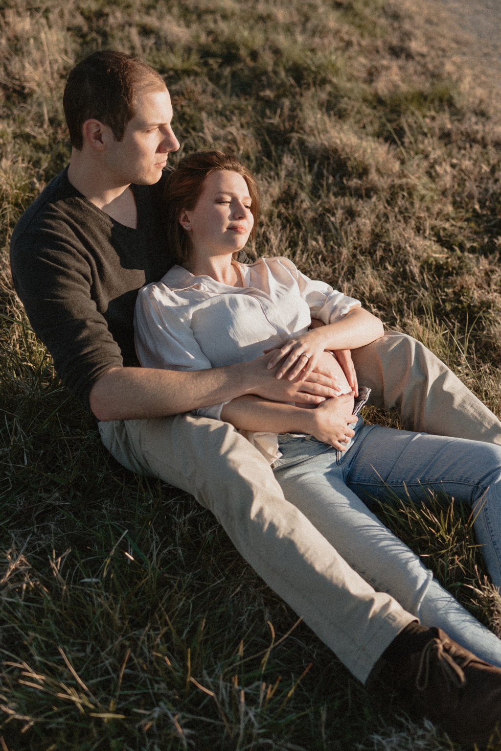 Pregnant couple lounging in field