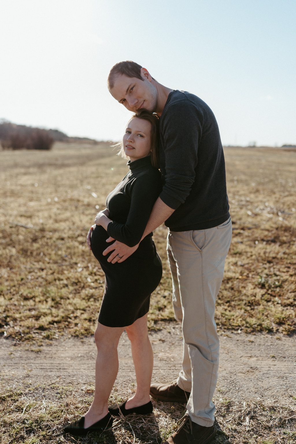 Man standing behind pregnant woman holding her belly