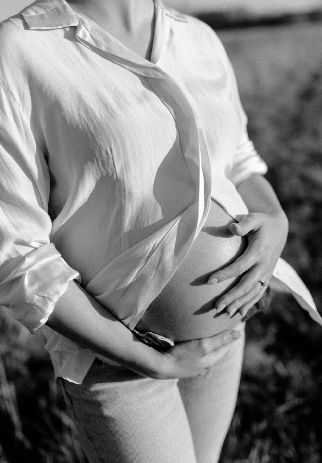 Pregnant woman rubbing belly in black and white