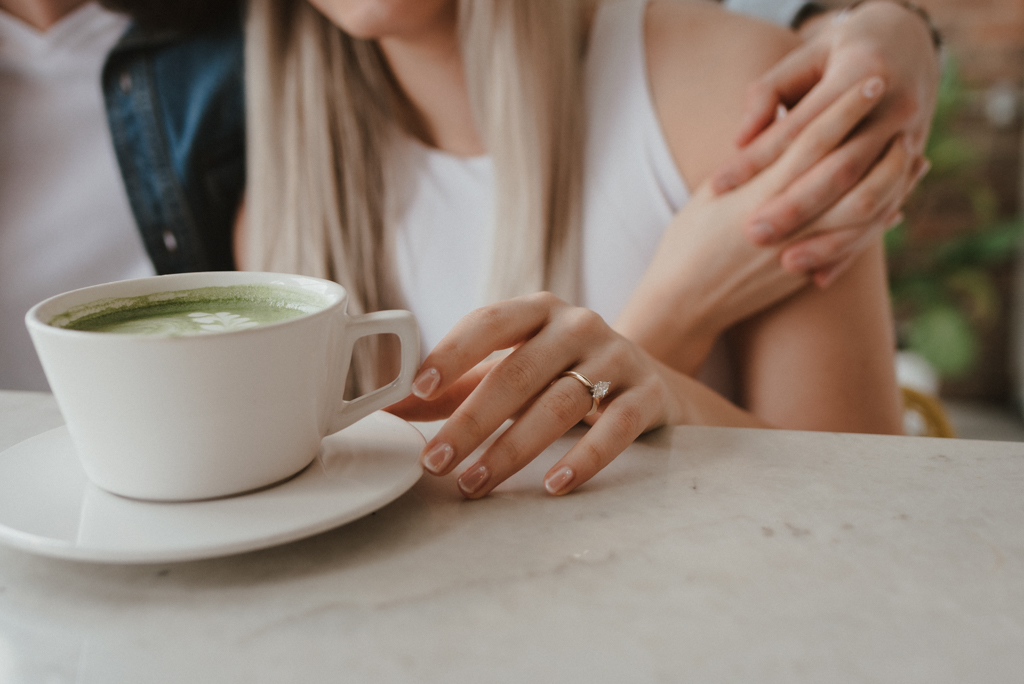 Woman's engagement ring on hand holding coffee cup