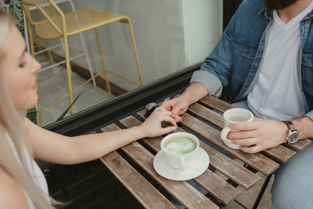 Couple holding hands while drinking coffees
