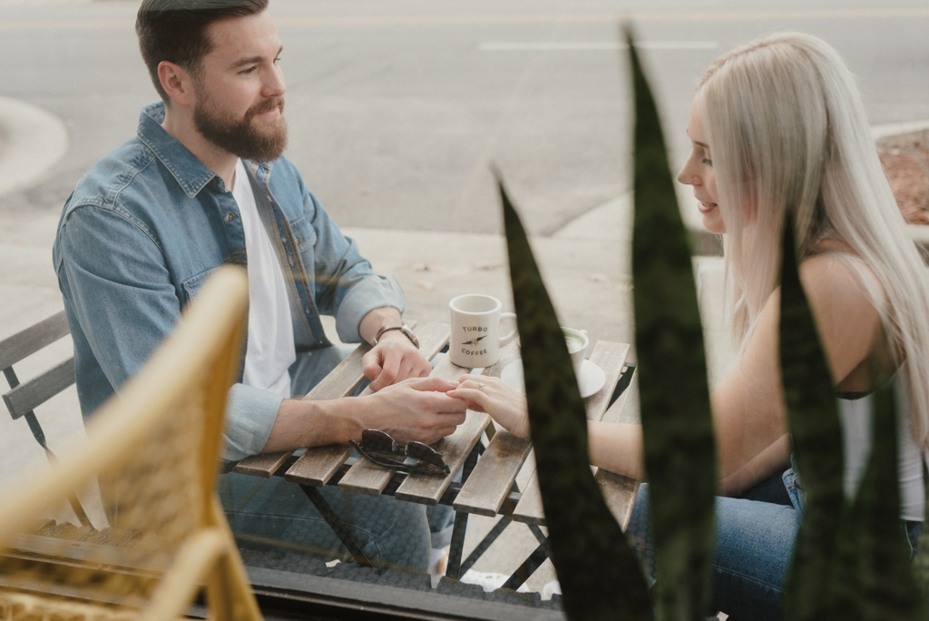 Couple sitting outside coffee shop holding hands