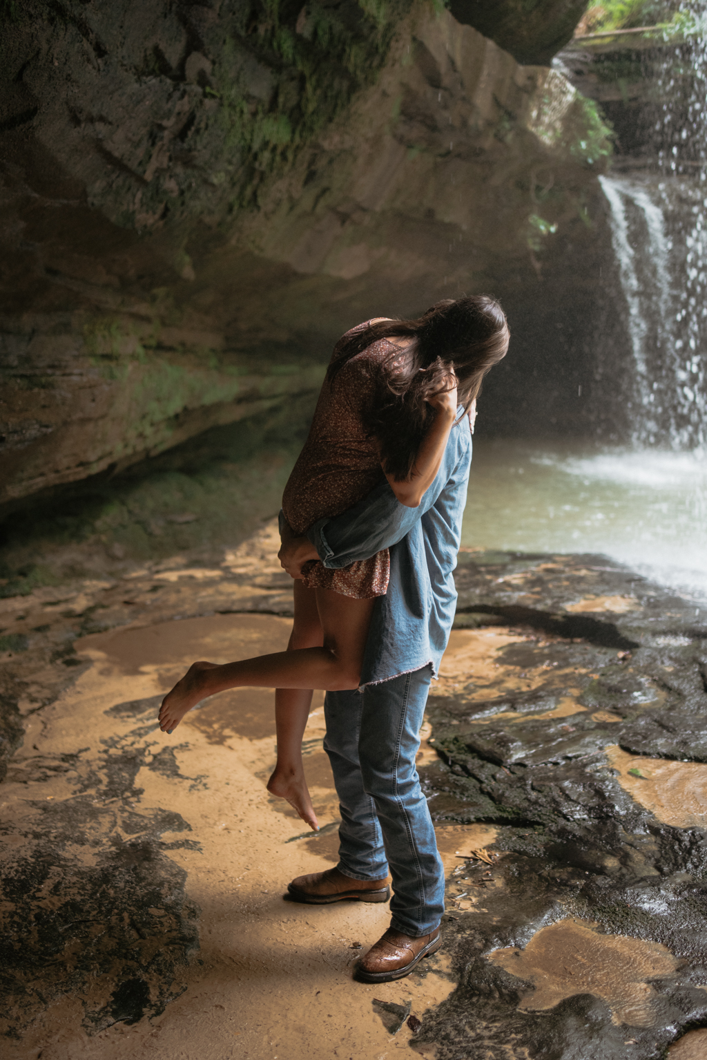 Man holding woman under waterfall