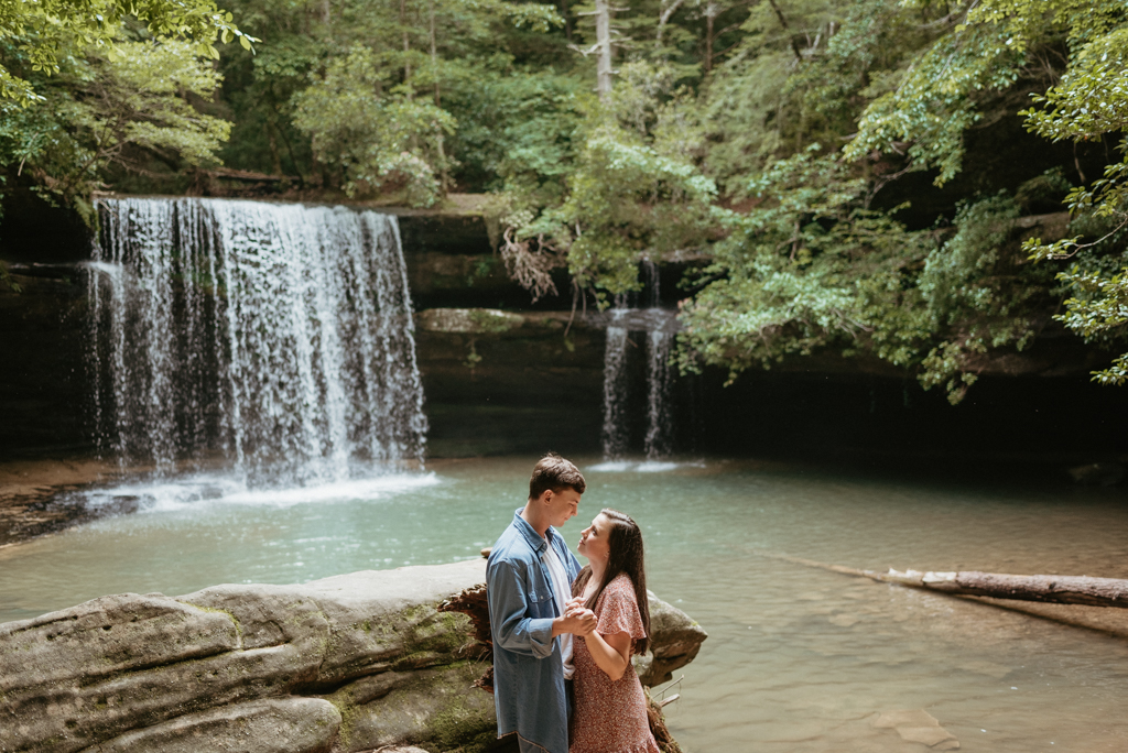 Man and woman slow dancing beside waterfall